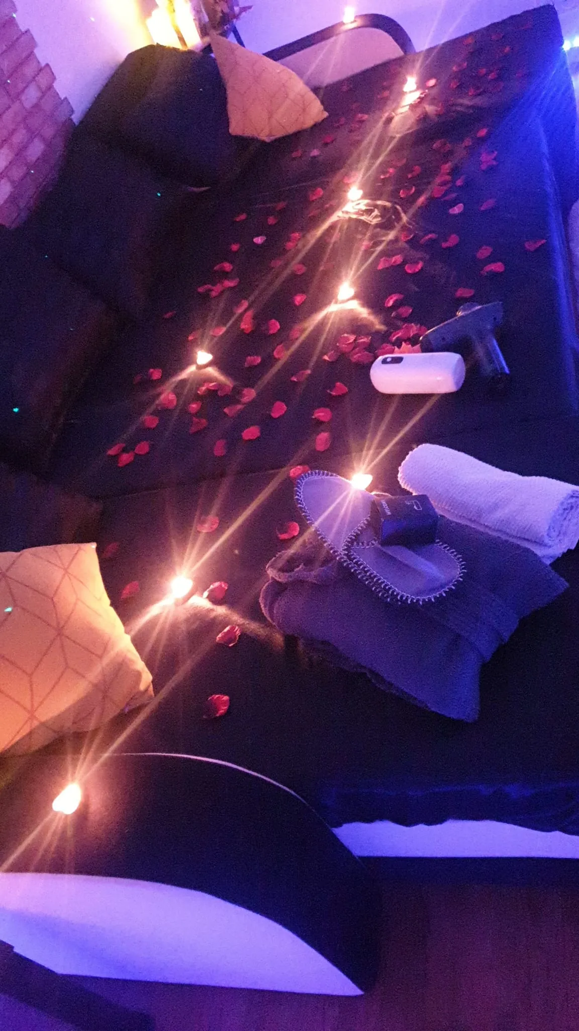 Canapé de massage avec coussins et pétales de rose sous ambiance violette