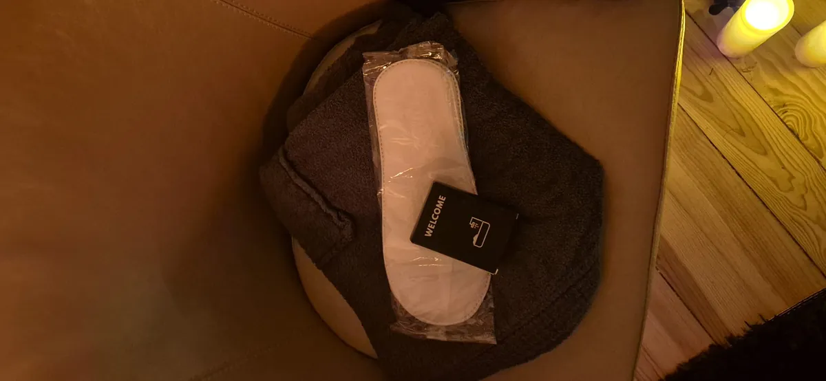 Chaussons de bienvenue et serviette posés sur le fauteuil