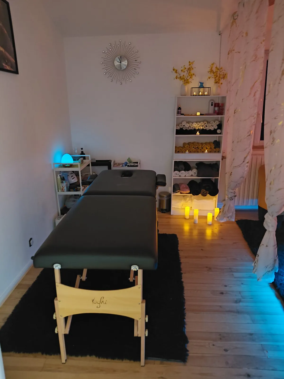 Salle de massage avec étagère de serviettes et bougies