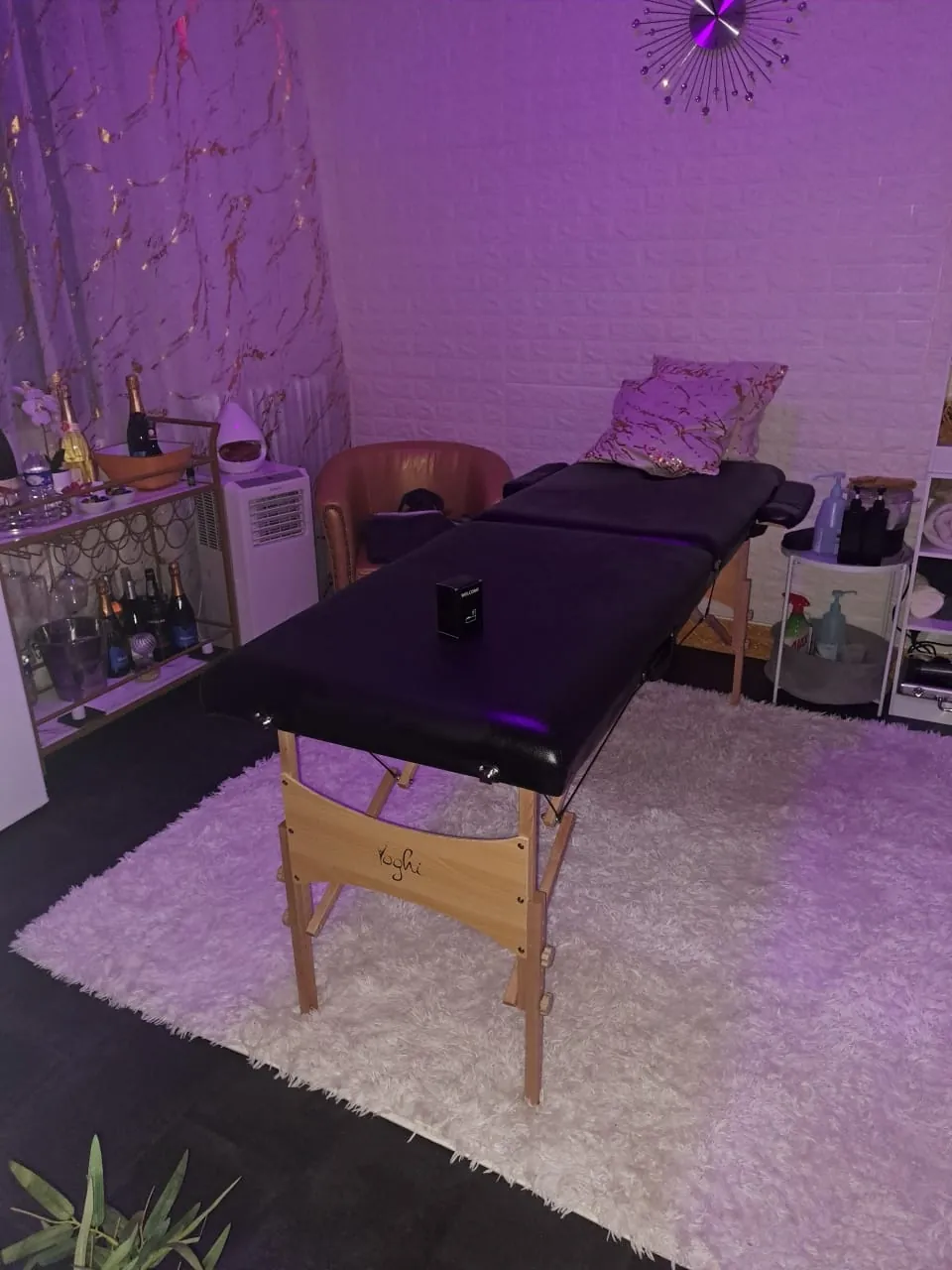 Salon privé du spa avec camille de massage noire et éclairage d'ambiance violet